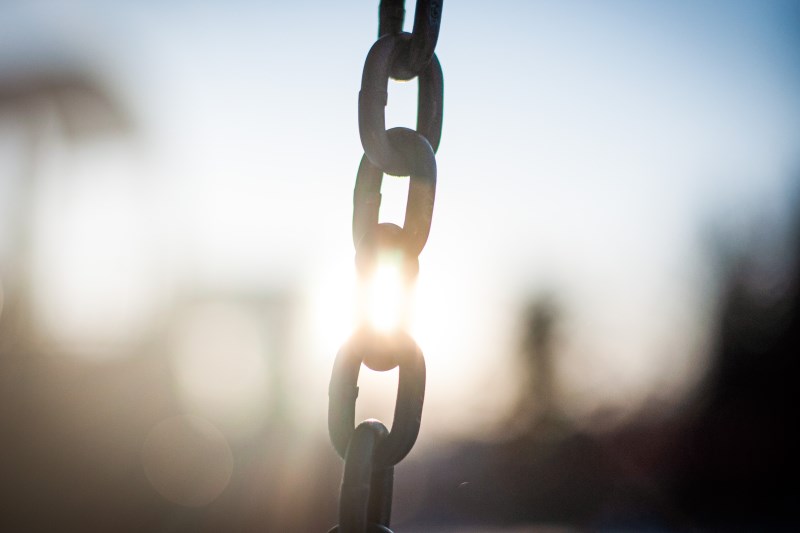 Close up of a metal chain in sunlight with blurry background